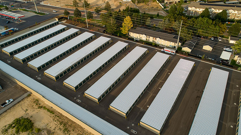 "An aerial view of a self-storage facility with multiple rows of storage units, showcasing the large, organized layout with a residential area in the background."